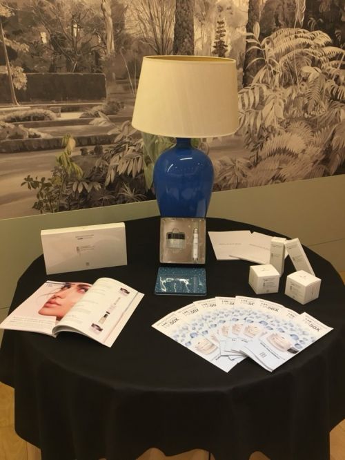 Muestrario de productos de estética expuestos en una mesa de una feria en un hotel